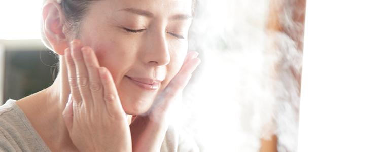 a woman giving herself a facial at home with a steamer 