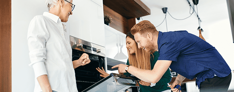 Couple open a wall oven to look inside when shopping for a new kitchen.