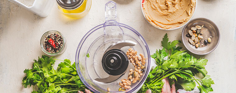 Mincing meat in a food processor with large tomatoes and lettuce in foreground.