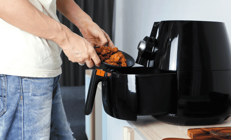 a man taking fried chicken out of the air fryer 