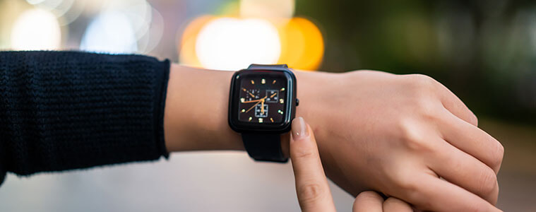 Close-up of a woman holding up her wrist to check the time on her black smartwatch.