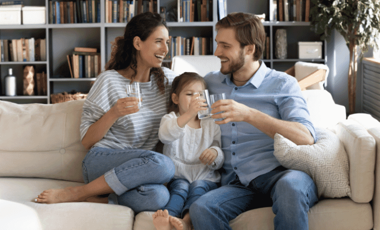 mum and dad sitting on the couch with their kid drinking water