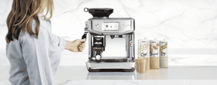 a woman using the Breville Barista Touch Impress Brushed Stainless