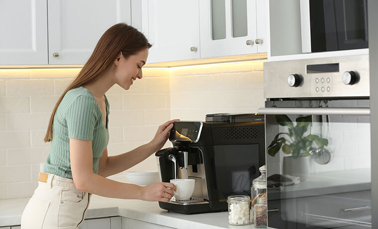 Young woman prepares fresh aromatic coffee with modern coffee machine in kitchen.