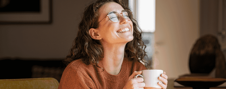 A lady holding a coffee cup smiling 