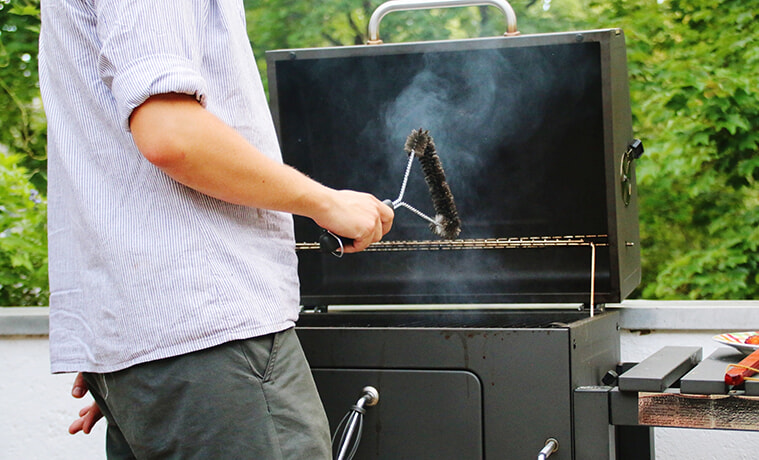 A man uses a cloth to clean the grill plate of his barbecue