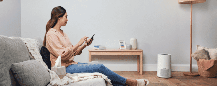 woman sitting on her couch controlling her Breville The Smart Air Viral Protect Plus