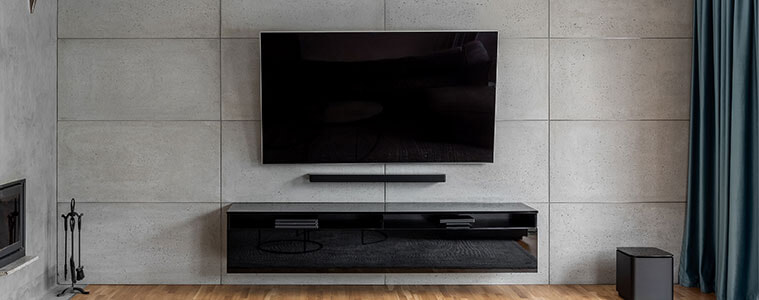 A wall-mounted TV and soundbar in a contemporary grey cement living room. 