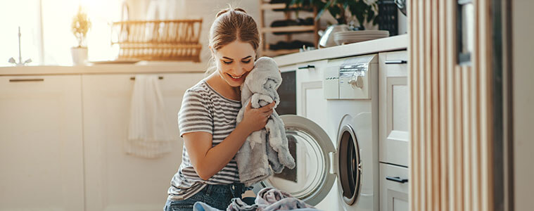 Happy woman doing the laundry in a new washing machine.