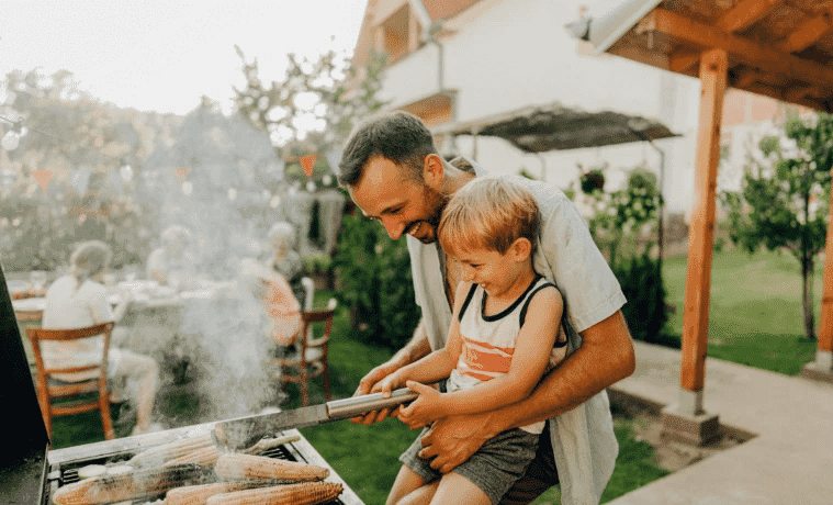 A dad cooking meat on the bbq with his son