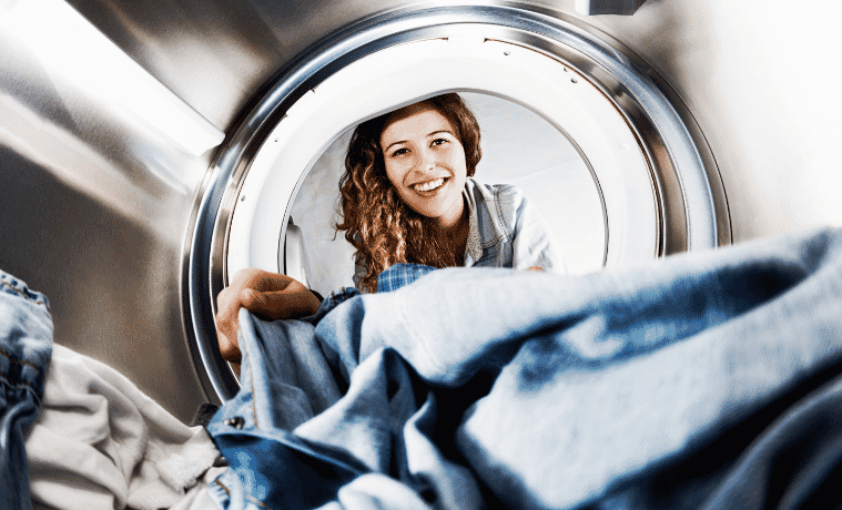 Internal view of a dryer as a woman unloads her clothes.