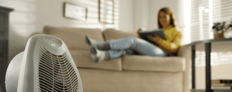 A lady relaxing next to an electric ceramic heater 
