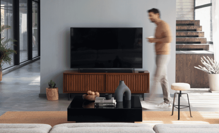 a man walking in his lounge room next to his Bose soundbar speaker 