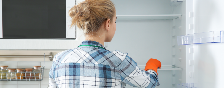 Lady cleaning out her fridge with orange gloves 