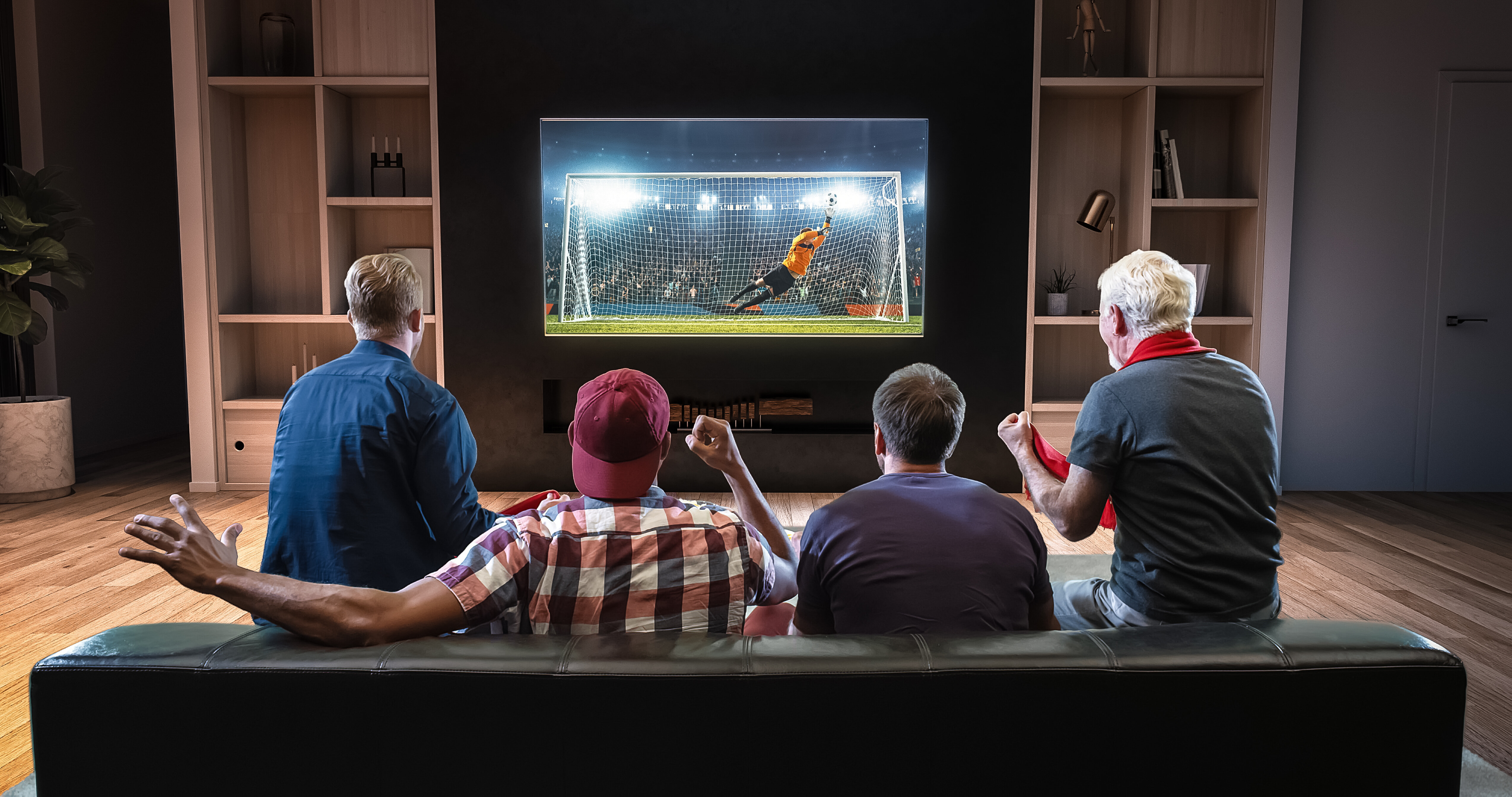 Group of fans watching a soccer moment on the TV and celebrating a goal, sitting on the couch in the living room