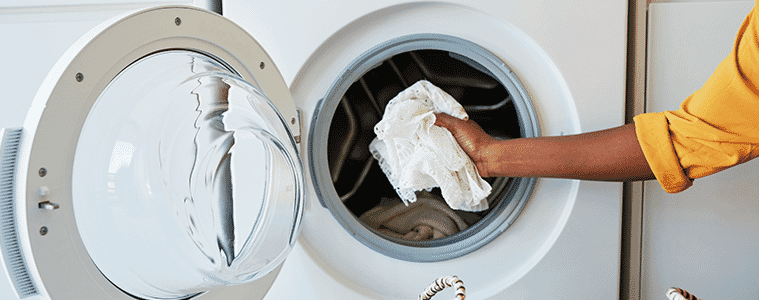 a woman reaching into her washing machine to get her laundry