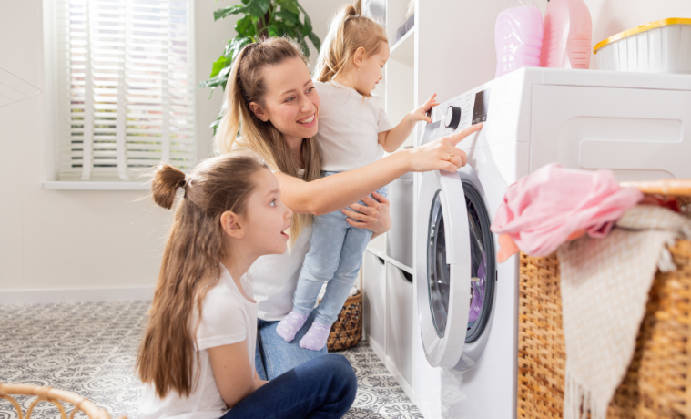 A mum doing washing with her children and showing them the washing machine