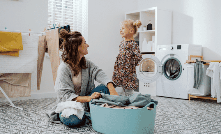 Mother and daughter in the laundry standing with a pile of washing