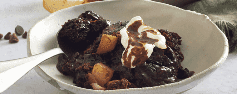 Oozy chocolate and pear self-saucing pudding in a ceramic bowl with a silver spoon. 