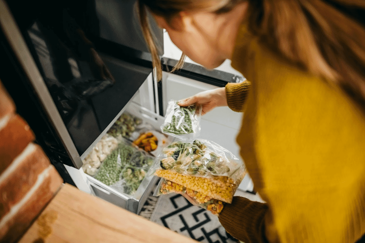 Woman putting portions of mixed vegetables into the freezer.