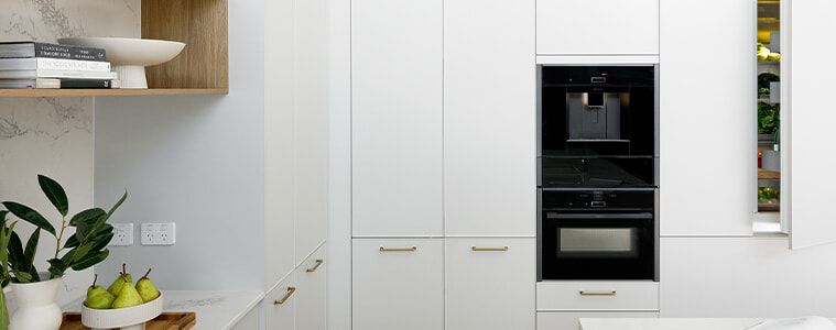 White coastal-style kitchen with marble-look island and herringbone floors.