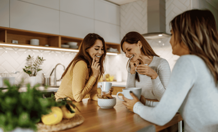 3 ladies sitting around a kitchen table drinking coffee