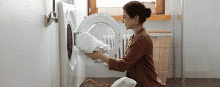 a woman pully out dried clothes from her white Bosch heat pump dryer 